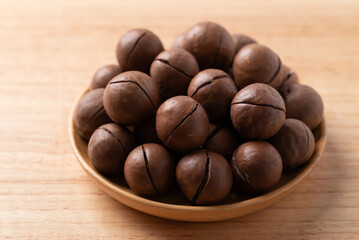 Macadamia nuts in a bowl on wooden background