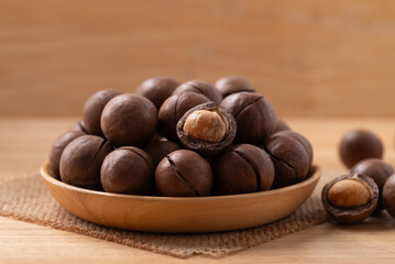 Macadamia nuts in a bowl on wooden background