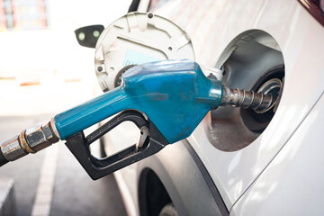 Old Blue Fuel Pump Nozzle Refueling a Car at a Gas Station. rising fuel prices, transportation costs, energy, and automobile maintenance. petrol consumption, gasoline, oil industry.