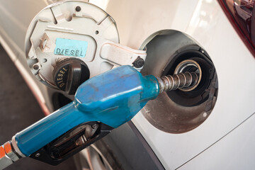 Old Blue Fuel Pump Nozzle Refueling a Car at a Gas Station. rising fuel prices, transportation costs, energy, and automobile maintenance. petrol consumption, gasoline, oil industry.