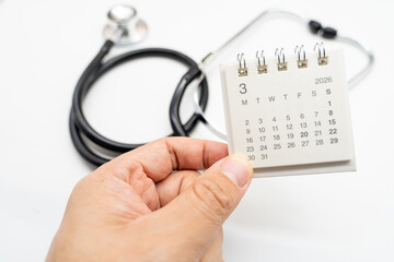 Hand holding desk calendar set to MARCH 2026. Doctor Appointment Schedule and Annual Health Checkup Reminder. Preventive medicine, healthcare planning, doctor visits, and timely examinations.