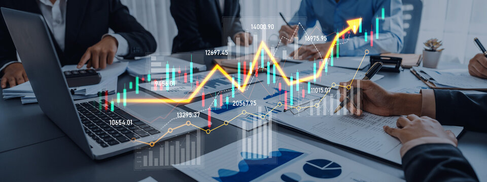 A dynamic business meeting showcasing teamwork in financial analysis. Professionals collaborate over charts and a laptop, discussing growth strategies and project planning. Scalp - Powered by Adobe