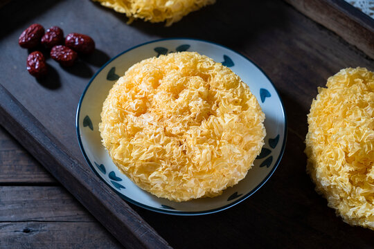 Dried Golden Tremella mushroom (Tremella aurantialba) on plate with red dates for healthy soup