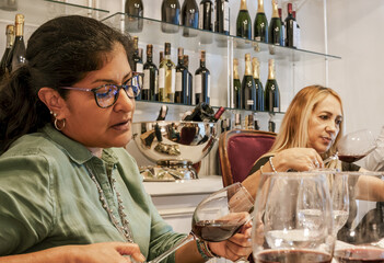 Women experiencing red wine tasting during social gathering