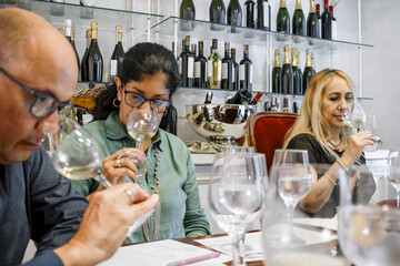 Three diverse adults enjoying a white wine tasting experience