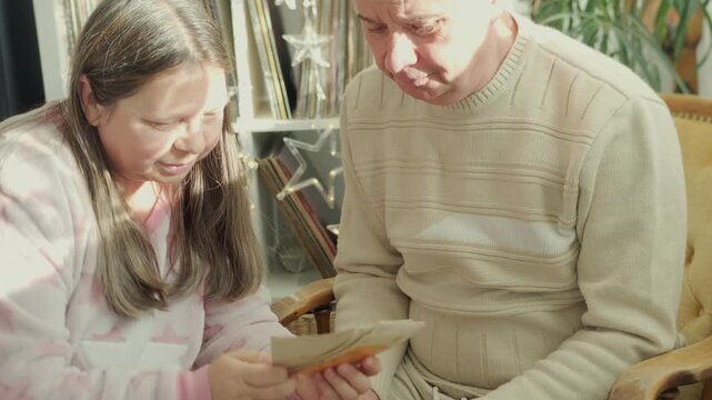 man and woman gently sort through old vintage black and white photographs 30s, 40s, evoking nostalgia and cherished memories past, timeless treasured stories, family history and forgotten moments