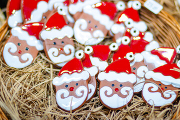 Colorful decorative cookies shaped like Santa Claus faces with red hats and white beards arranged in a rustic basket, creating a festive holiday atmosphere for celebrations
