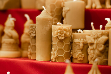 Decorative candles in various shapes and sizes displayed on a vibrant red background, showcasing intricate designs and textures, perfect for home decor and ambiance enhancement