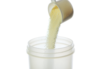Carefully measuring and pouring fine powdered nutritional supplement from a scoop into a transparent container, emphasizing precise preparation for health and wellness