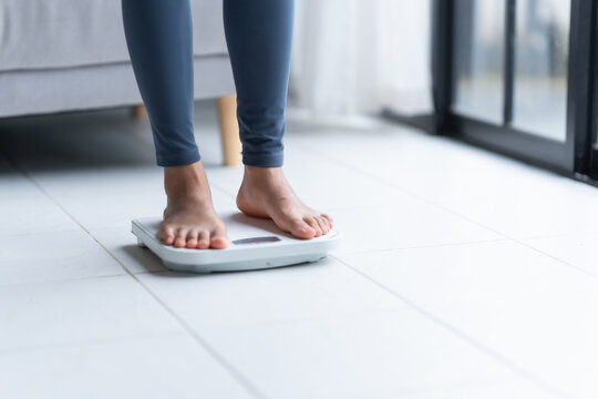 Fat diet and scale feet standing on electronic scales for weight control. Measurement instrument in kilogram for a diet control.