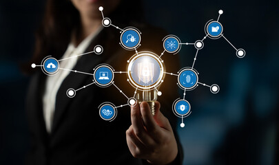 A businesswoman showcases a glowing light bulb symbolizing innovation, surrounded by digital connectivity icons, representing modern technology in a dark backdrop. Crux