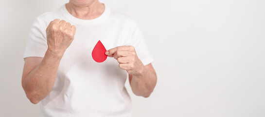 Elderly woman with red Blood drop paper for concept of June World Blood Donor day, Donation, January Blood donor awareness month, April Hemophilia awareness day, May Thalassemia Day, Anemia awareness