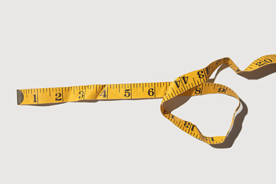 Yellow measuring tape in inches on a white background