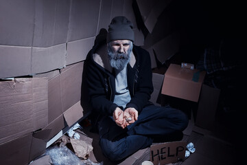 A homeless bearded man sits on boxes on the street and asks for help. Need a homeless person asks...