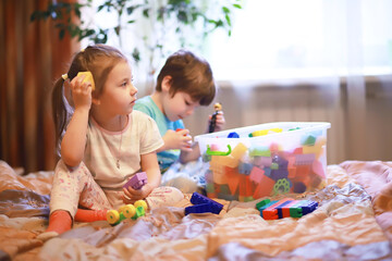 Fototapeta premium Children play construction set sitting on the sofa and watch cartoons on TV.