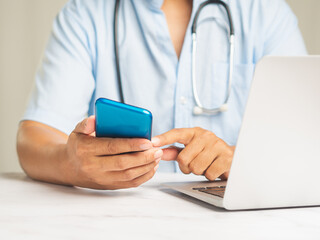 Doctor using smartphone for telemedicine at office desk.