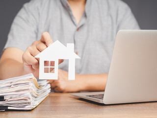 Man holding paper house model for real estate concept.