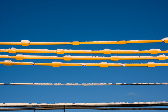 Snow covered yellow insulated power lines with clear blue sky