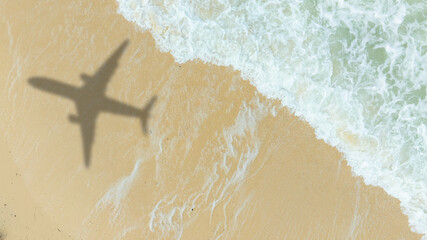 Aerial view of shadow passenger plane silhouette and sandy beach blue sea with waves at sea beach summer vacation sea travel concept	
