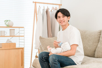 Father feeding baby with a bottle on the sofa at home, baby, infant