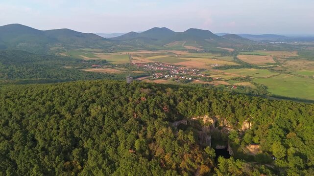 Breathtaking drone view of the Tarn of Megyer-hegy, lookout and K&aacute;rolyfalva in Hungary, highlighting lush forests, tranquil lake and surrounding countryside around a historic former millstone quarry.