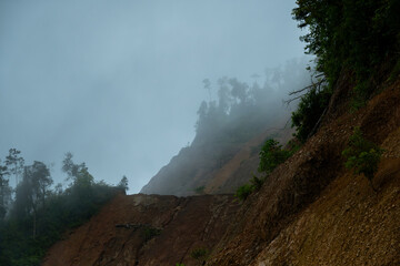 Dark and gloomy forest scenery on mountain layers landscape in Jantho, Aceh, Indonesia, with thick fog that limits visibility