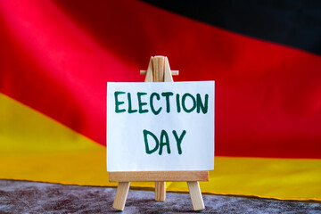 Paper note with words ELECTION DAY on National symbol of Germany. German wave silky flag background. Concept of election political participation campaign and civic engagement 
