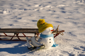 Cute winter snowman. Snow man with carrot nose outdoors. Cozy snowman in bright snow. Snowman for Christmas background. Happy snowman scene.
