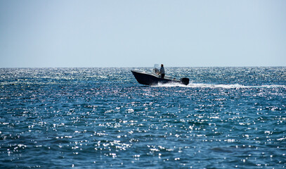 Speed boat cuts through waves. Boat shines under sun. Speed boat glides across blue water. Speed...