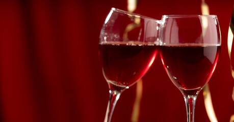 Two red wine glasses against a burgundy bokeh background, studio shot. Background for celebrations, wedding dinners, New Year's, Valentine's Day, and dating 