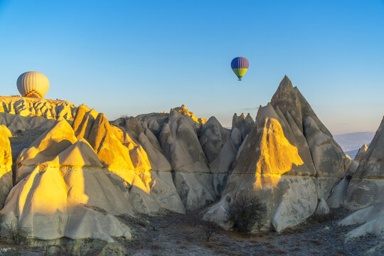 Hot air balloons flying above fairy chimneys in Cappadocia at sunrise