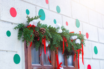 Festive Christmas tree decorated with red ribbons, gold and red ornaments, pinecones, and warm holiday light against a brick wall background.