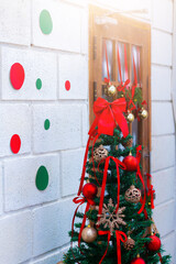 Festive Christmas tree decorated with red ribbons, baubles, and ornaments beside a window, creating a warm holiday atmosphere.