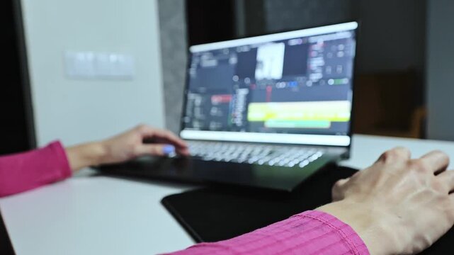 Woman in pink works from home editing content for digital media campaigns