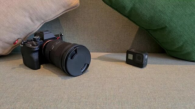 Mirrorless camera and an action camera sit on a sofa for a clean product display shot, ideal for technology, photography gear, video equipment and consumer electronics themes