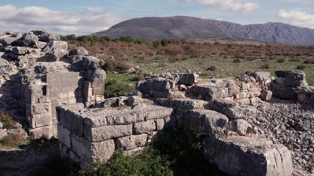 Close-up view of ancient Daorson Illyrian city ruins near Stolac, Bosnia and Herzegovina, showing massive stone blocks, collapsed walls and a wide mountain landscape under clear autumn light.
