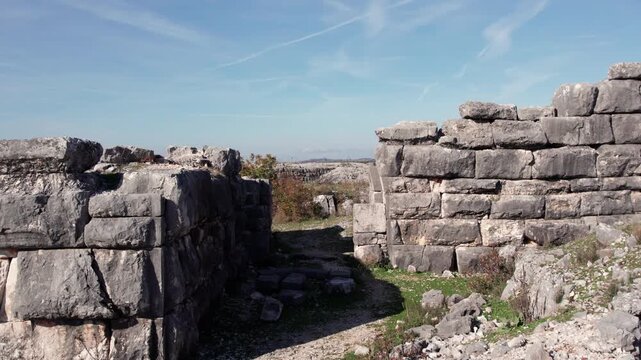Ancient stone gateway and massive Illyrian fortress walls of Daorson near Stolac in Bosnia and Herzegovina, captured in bright daylight with rugged terrain and clear sky highlighting the historic site