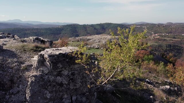Panoramic view of the Daorson Illyrian ruins near Stolac, showing stone remains, rocky terrain, and forested hills under a clear sky.