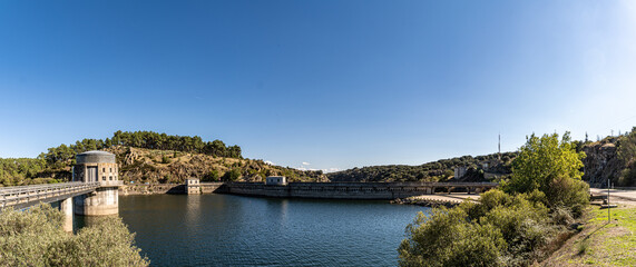 Fototapeta premium Panoramic view of reservoir dam and water landscape under clear blue sky with copy space