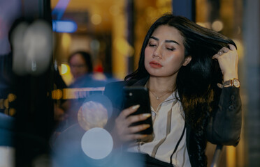 Successful asian businesswoman sitting in the cafe at night and chatting by phone.
