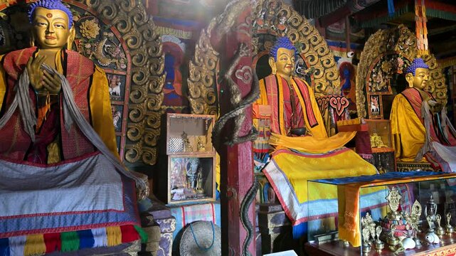 Inside Mongolia's Erdene Zuu Monastery: three ancient gilded Buddhist statues, ritual drums, and ornate altars display traditional artistry within the country's oldest temple complex.