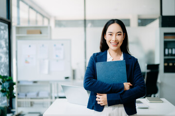 Confident Asian businesswoman pointing in a modern office. Professional female leader presenting ideas with copy space, ideal for business, marketing, leadership