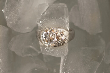 Top view on unique beautiful handmade silver ring inspired by natural textures with gemstones on ice cubes.