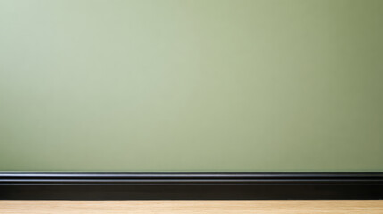 Simple green wall with black trim and wooden floor in an indoor space during daylight