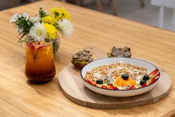 Healthy granola fruit bowl with iced tea on wooden table