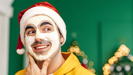 Skincare For Men Christmas Man wearing a Santa hat and facial mask smiling indoors with festive decorations in the background.