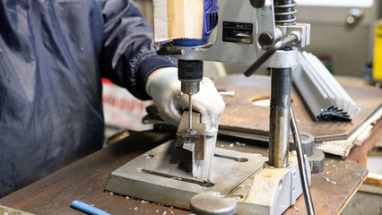 Precision drilling of an aluminum frame using a drill press in a factory