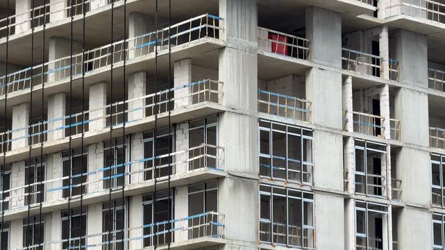 Construction site of unfinished building with concrete frames and glass windows in urban area