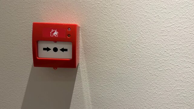 Fire alarm button on wall casting shadow, emergency equipment concept, usable as background