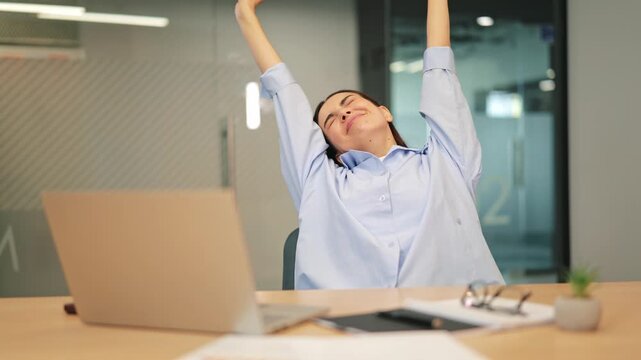 Employee feels tired, yawns and stretches, fighting fatigue during office workday. Concentration is difficult when sleepy. Exhaustion is visible on face, seeking relief with a stretch.